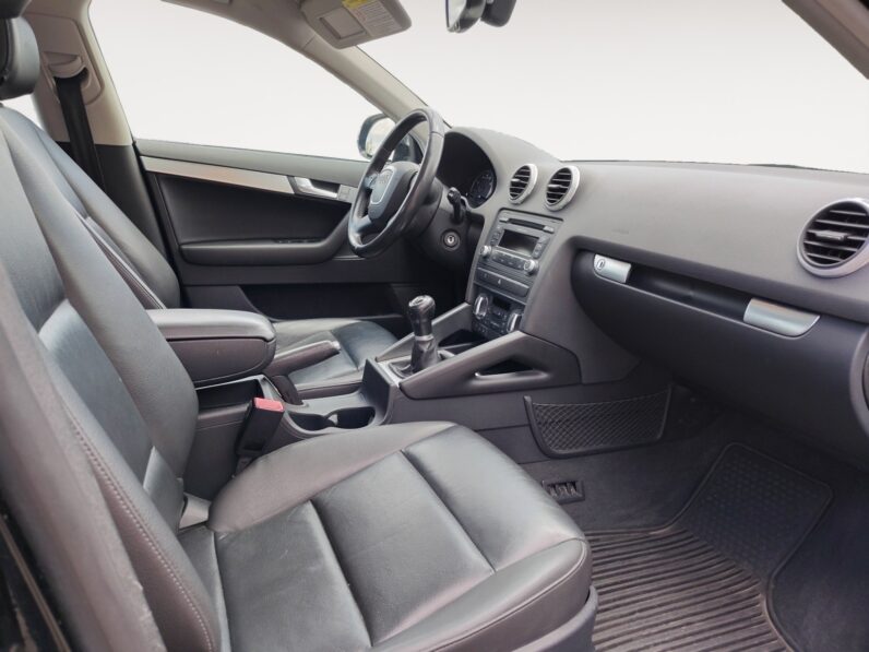 Interior view of a 2009 Audi A3 featuring black leather seats, a modern dashboard, gear shift, and control panel, highlighting the vehicle's luxury and comfort.