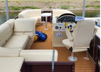 Interior of a Canalake Double Decker boat featuring comfortable seating, steering console, and a scenic water view, highlighting leisure and outdoor activities.