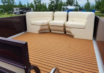 Interior seating area of a Canalake Double Decker boat, featuring beige cushioned seats and wooden flooring, suitable for leisure and relaxation.