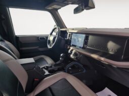 Interior view of a 2022 Ford Bronco Wildtrak Sasquatch showcasing modern dashboard, steering wheel, and seating, emphasizing its rugged design and off-road capability.