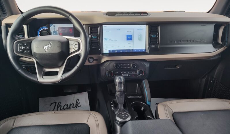 2022 Ford Bronco Wildtrak Sasquatch interior featuring steering wheel, large touchscreen display, and gear shift, showcasing modern technology and spacious design.
