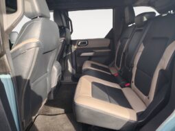 Interior view of the rear seating area in a 2022 Ford Bronco Wildtrak Sasquatch, featuring spacious seating with a combination of black and beige upholstery, highlighting the vehicle's comfort and design for adventurous journeys.
