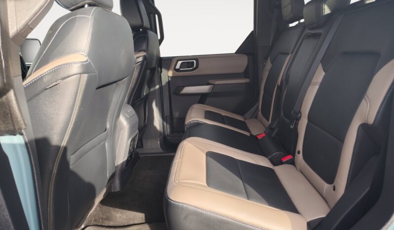 Interior view of the rear seating area in a 2022 Ford Bronco Wildtrak Sasquatch, featuring black and tan upholstery, spacious seating for passengers, and modern design elements.