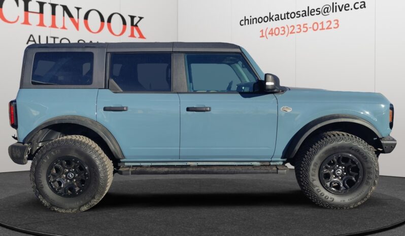2022 Ford Bronco Wildtrak Sasquatch in blue, showcasing a side view with off-road tires, set against a neutral background featuring Chinook Auto Sales branding.