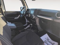 Interior view of a 2018 Jeep Wrangler Unlimited Sahara, showcasing black seating, dashboard controls, and a "Thank You" note, emphasizing the vehicle's adventure-ready design.