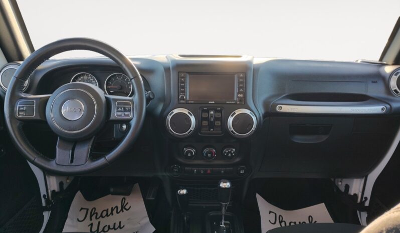 Jeep Wrangler Unlimited Sahara 2018 interior dashboard featuring steering wheel, touchscreen display, and climate controls, emphasizing adventure-ready design and modern features.