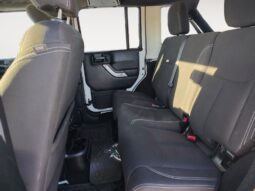 Interior view of the rear seating area in a 2018 Jeep Wrangler Unlimited Sahara, featuring black upholstery and spacious seating for passengers.