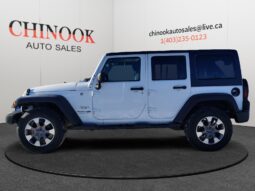 2018 Jeep Wrangler Sahara Unlimited 4&times;4 in white, showcasing side profile against a neutral background, featuring Chinook Auto Sales branding and contact information.