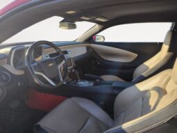 Interior view of a 2014 Chevrolet Camaro 2LT, featuring beige leather seats, a stylish dashboard with Chevrolet branding, and a modern console design, showcasing the vehicle's luxury and performance attributes.