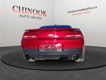 Chevrolet Camaro rear view in red, displayed at Chinook Auto Sales, showcasing dealership branding and contact information.
