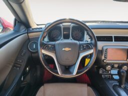 Chevrolet Camaro 2LT steering wheel and dashboard interior, featuring beige accents and modern controls, highlighting the vehicle's luxurious design and performance capabilities.