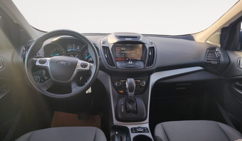 Interior view of a 2015 Ford Escape SE showcasing dashboard, steering wheel with Ford logo, and infotainment system, emphasizing comfort and technology features for potential buyers.