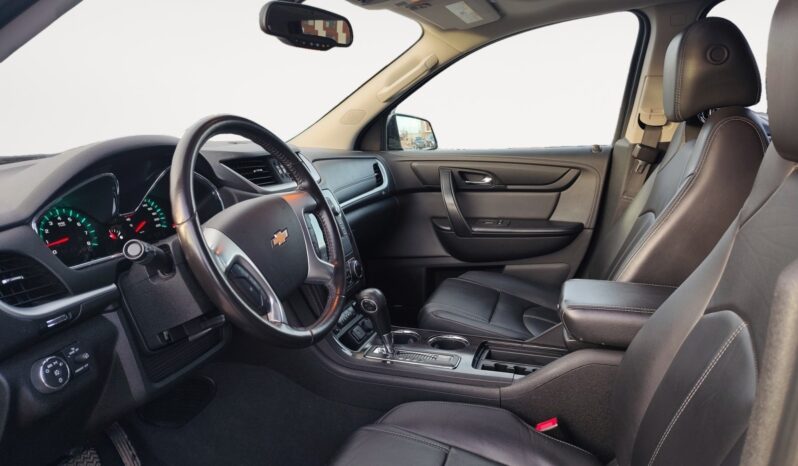 Interior view of a 2017 Chevrolet Traverse 2LT AWD, featuring black leather seating, dashboard with gauges, and center console, highlighting comfort and spaciousness for families.