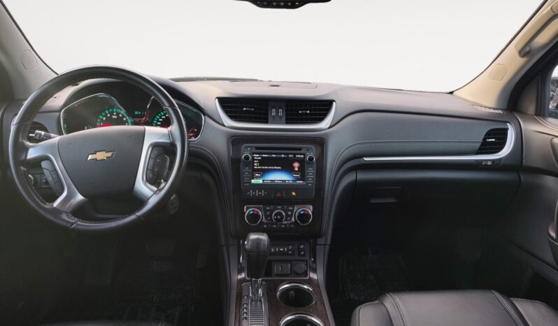 Interior view of 2017 Chevrolet Traverse 2LT AWD, featuring steering wheel with Chevrolet logo, dashboard with infotainment system, climate controls, and black leather seats, highlighting comfort and functionality for family use.