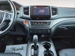 Honda Pilot EXL-R interior view showcasing center console, touchscreen display, gear shift, and cup holders, emphasizing modern design and user-friendly features for family-oriented SUV.