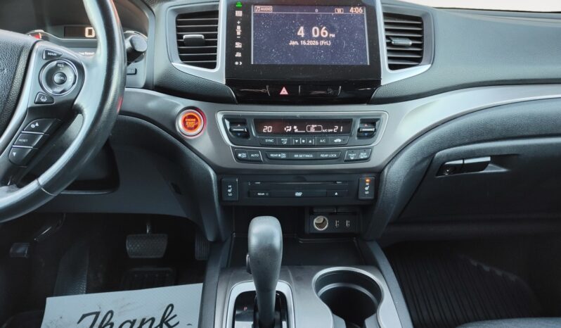 Interior view of 2016 Honda Pilot EXL-R dashboard with touchscreen display, climate controls, gear shift, and steering wheel, emphasizing features for family-friendly driving.