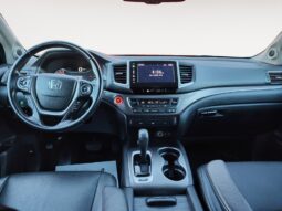 Honda Pilot EXL-R interior showcasing steering wheel, dashboard, touchscreen display, and center console with gear shifter, emphasizing premium comfort and family-friendly features.