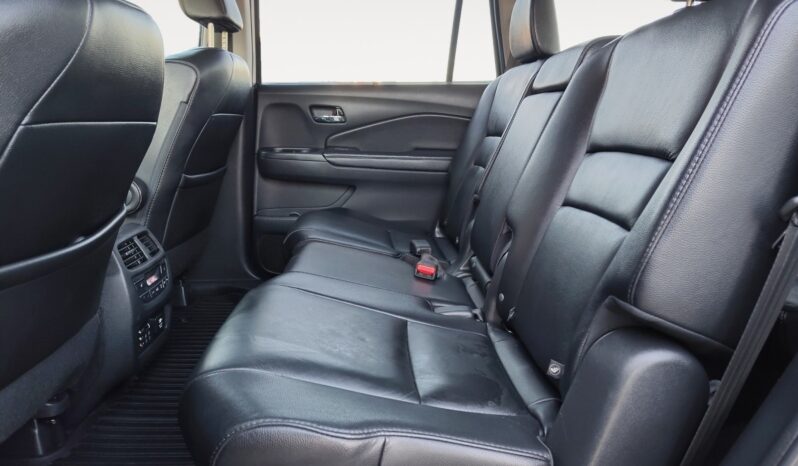 Interior view of the rear seating area in a 2016 Honda Pilot EXL-R, featuring black leather upholstery and ample space for passengers, highlighting family-friendly design.